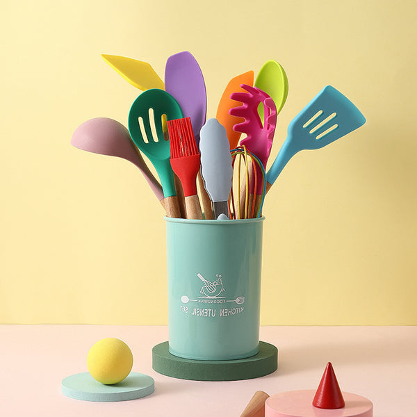 Colorful silicone cooking utensils in a teal holder against a pastel background, showcasing a kitchen tool set.