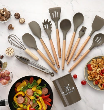 Set of silicone kitchenware cooking utensils with wooden handles on a countertop, featuring a variety of tools for cooking and baking.