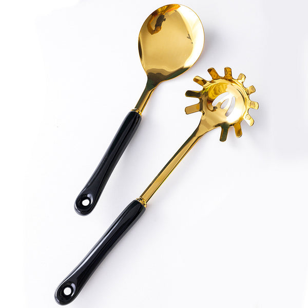 Gold kitchen utensils set featuring a slotted spoon and serving spoon with black handles, perfect for stylish cooking.