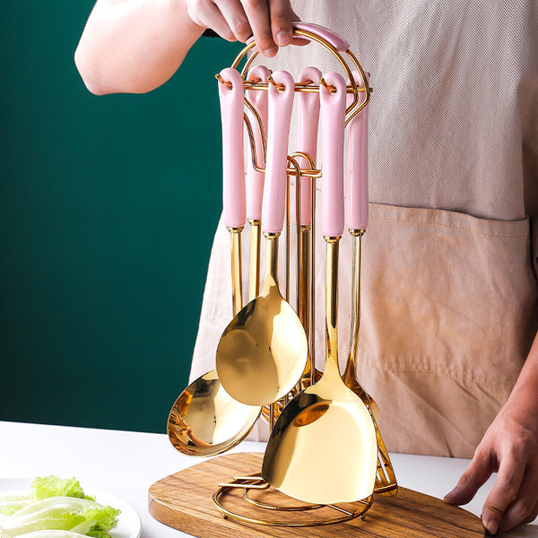 Stainless steel kitchen utensils set with pink handles, elegantly displayed on a holder, ideal for modern kitchens.