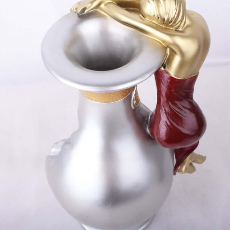 Handmade silver wine jug with a gold and red female figure holding the side, perfect for decorative use.