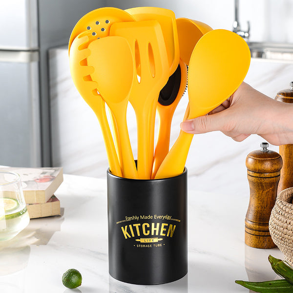 Yellow silicone cooking utensils set in modern black storage tube, ideal for baking and cooking.