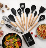 Silicone kitchen utensils set with wooden handles, including spatulas, whisk, and tongs, on a marble countertop.