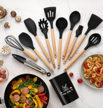 Silicone kitchen utensils set with wooden handles, including spatulas, whisk, and tongs, on a marble countertop.