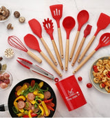 Red silicone kitchenware set with wooden handles, including spatulas, spoons, and tongs on a marble surface.