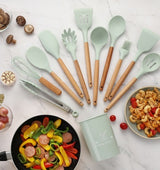 Set of mint green silicone kitchen utensils with wooden handles, featuring spatulas, whisk, and tongs, on a countertop with food.