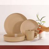 Elegant beige ceramic baking utensils set including plates and a mug on a stylish countertop.